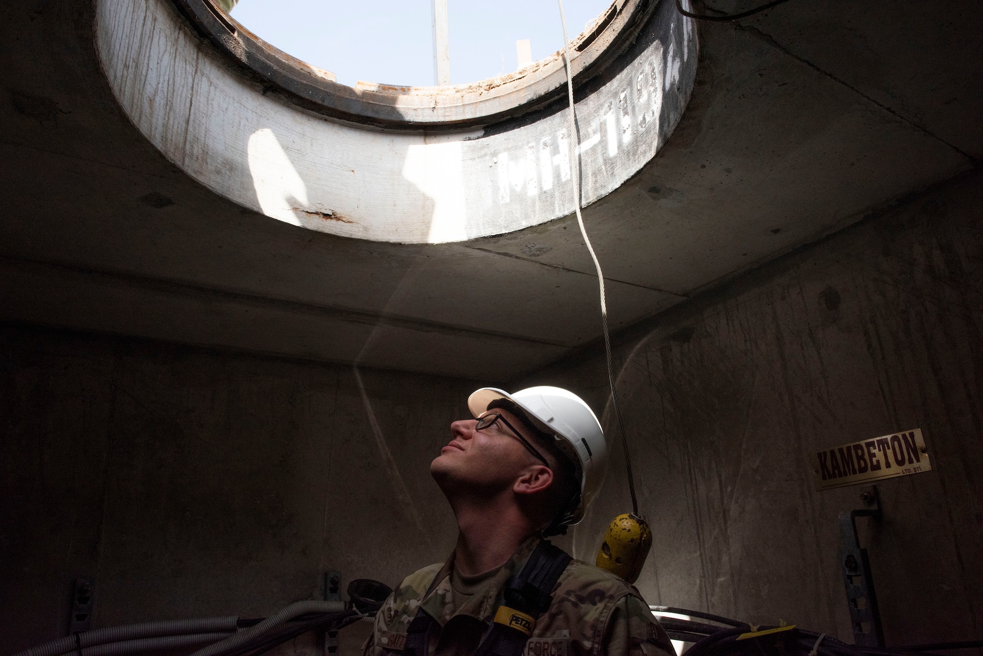 Photo of Airman staring up through a manhole