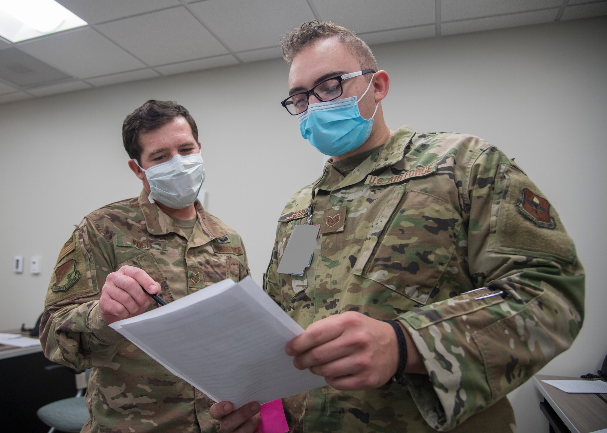 Tech. Sgt. Shawn Koch, left, 49th Wing self-assessment program manager, looks over medical documents, May 27, 2020, with Staff Sgt. Louis Koconis, right, 49th Operational Medical Readiness Squadron public health interim flight chief, at the 49th Medical Group public health call center on Holloman Air Force Base, N.M. Koch volunteered at the call center for approximately two months. His duties included assisting callers with their questions, ranging from Holloman’s current traveling policy to general COVID-19 related questions, ensuring everyone stayed safe and informed during COVID-19. (U.S. Air Force photo by Senior Airman Collette Brooks)