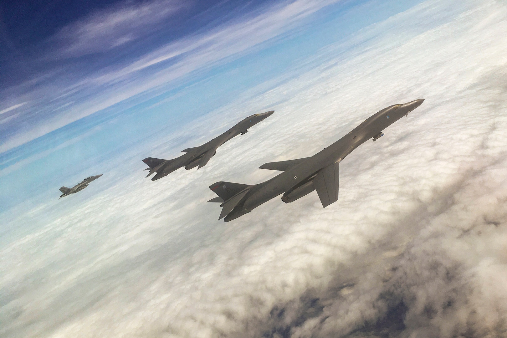 Three aircraft fly above the clouds.