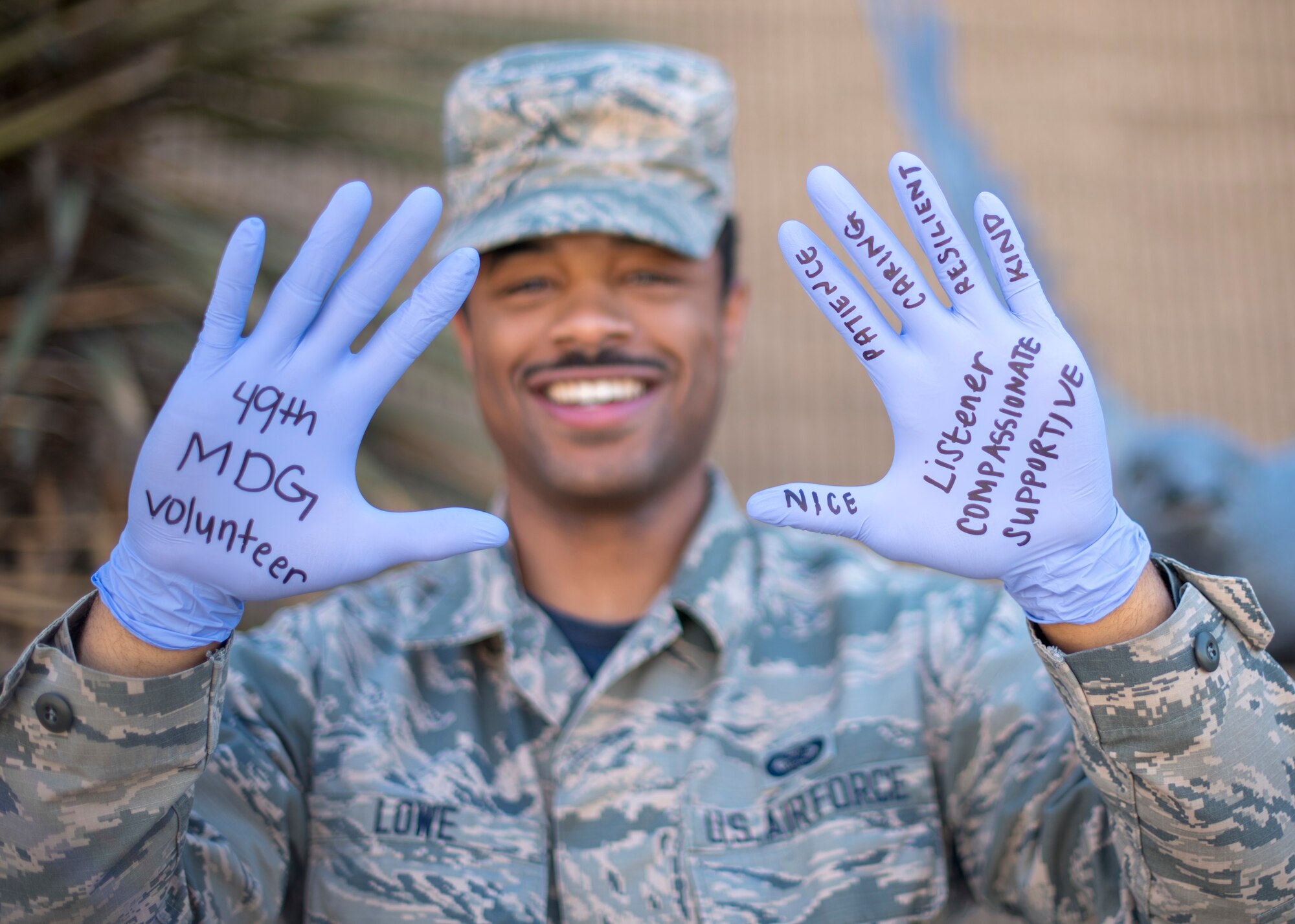 Airman 1st Class Quion Lowe, 49th Wing photojournalist, poses for a photo, May 29, 2020, at the 49th Wing on Holloman Air Force Base, N.M. The words written on his gloves represent the characteristics 49th Medical Group volunteers possess. (U.S. Air Force photo by Senior Airman Collette Brooks)
