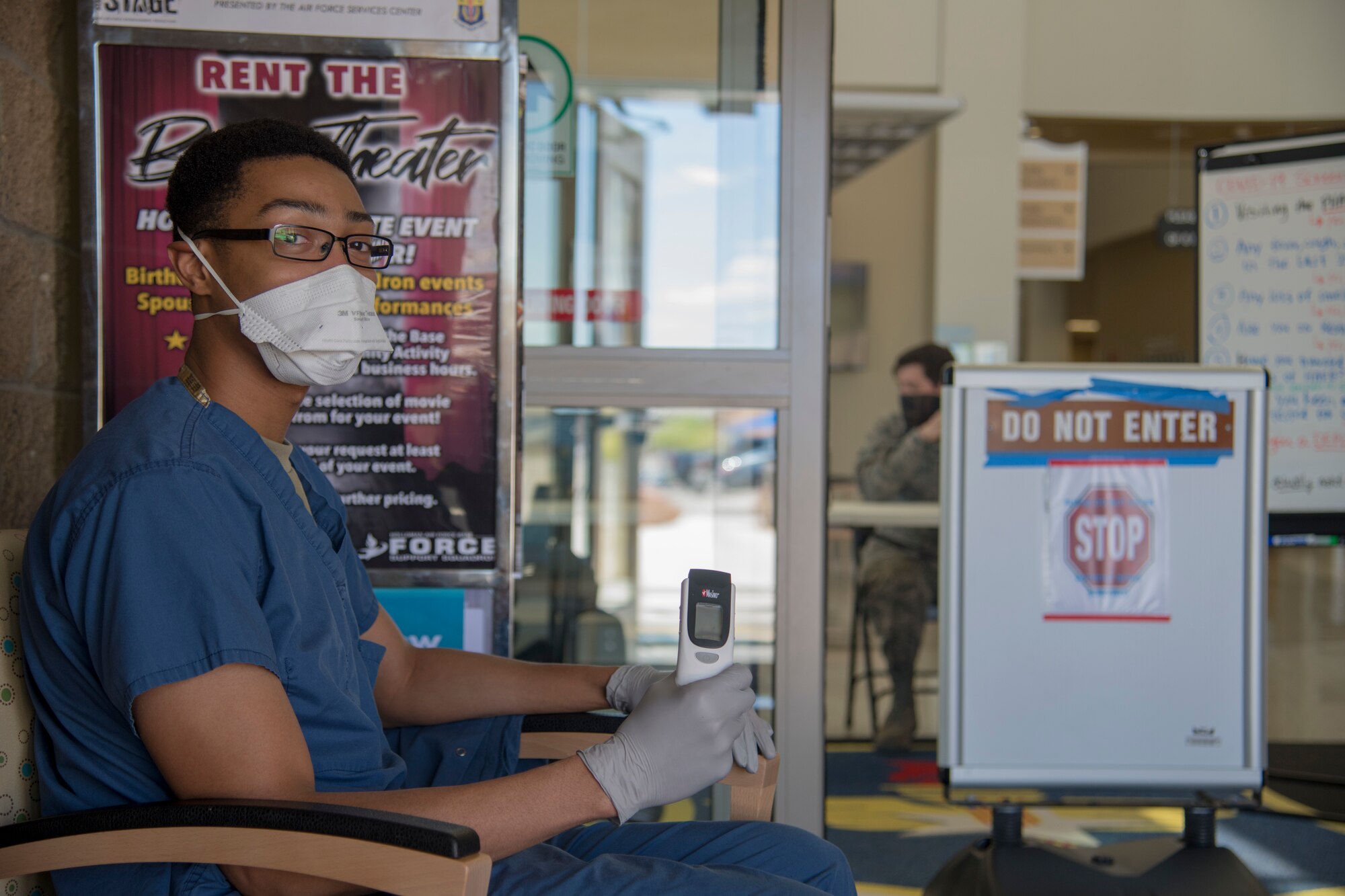 Staff Sgt. Desmond Gray, Operational Medical Readiness Squadron dental assistant, poses for a photo holding a thermometer, May 27, 2020, at the 49th Medical Group entrance on Holloman Air Force Base, N.M. Medical group volunteers took the temperature of personnel attempting to access the medical group in order to assess whether each individual was displaying COVID-like symptoms. (U.S. Air Force photo by Senior Airman Collette Brooks)