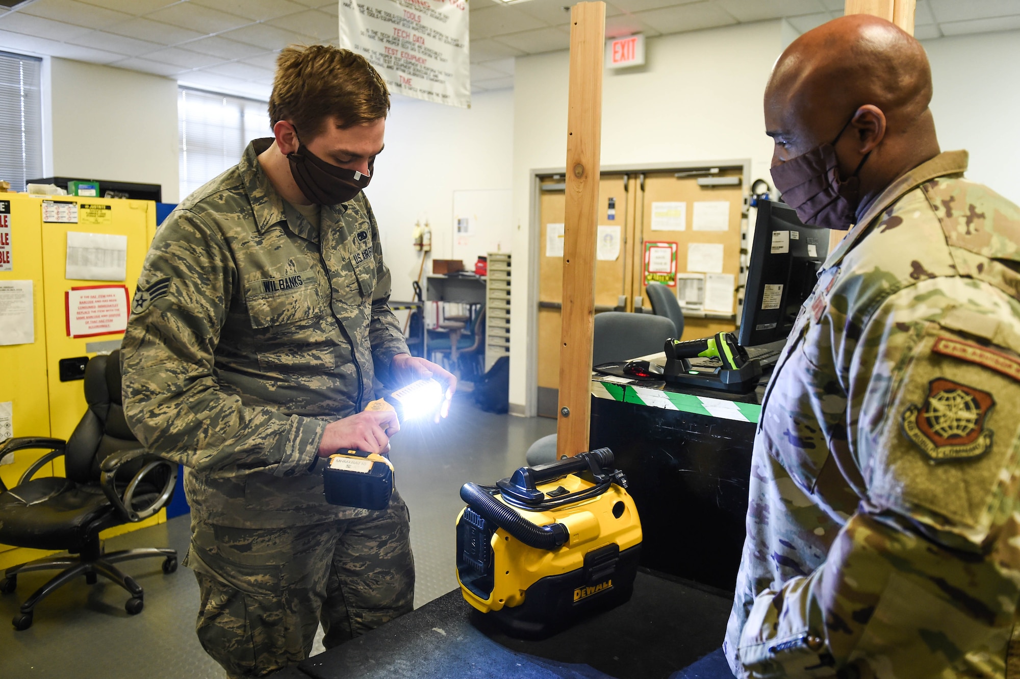 Senior Airman Michael Wilbanks, 62nd Maintenance Squadron support section journeyman, left, tests a flashlight before checking it out to Senior Master Sgt. John Williams, 62nd Mainenance Squadron flight chief, right, inside the home station check support section on Joint Base Lewis-McChord, Wash., May 20, 2020. The support section provides tools and equipment to maintenance personel who work on the aircrafts. (U.S. Air Force photo by Airman 1st Class Mikayla Heineck)
