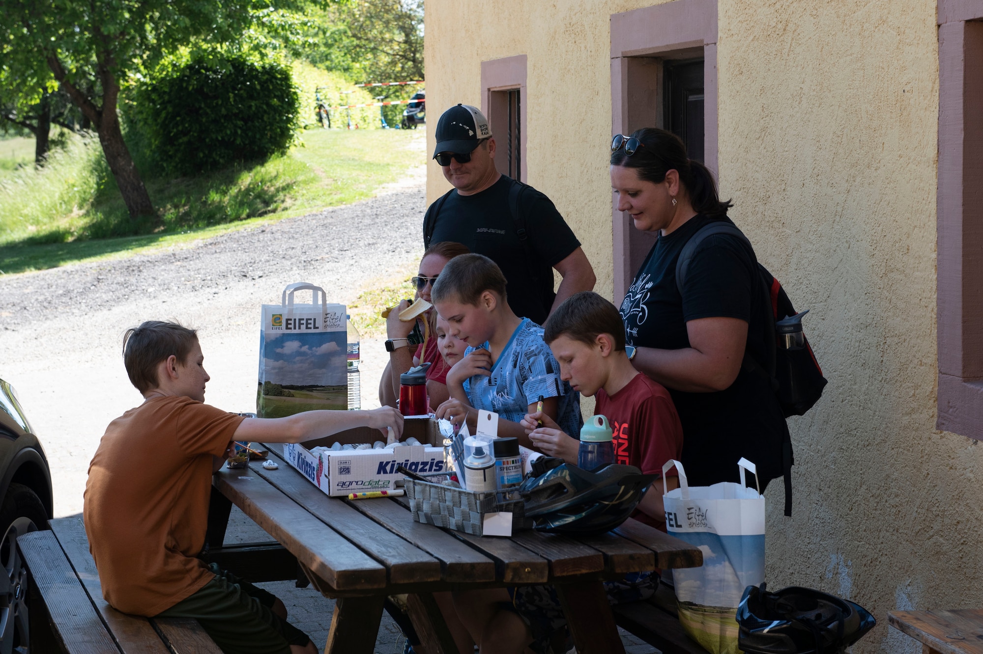 A Spangdahlem Air Base family eats snacks after a six-kilometer walk around Spangdahlem, Germany, May 29, 2020. The end of the walk led participants to a venue where they could sit and relax with snacks and beverages provided by the host nation council, and spend time with the other participating families. (U.S. Air Force photo by Senior Airman Melody W. Howley)