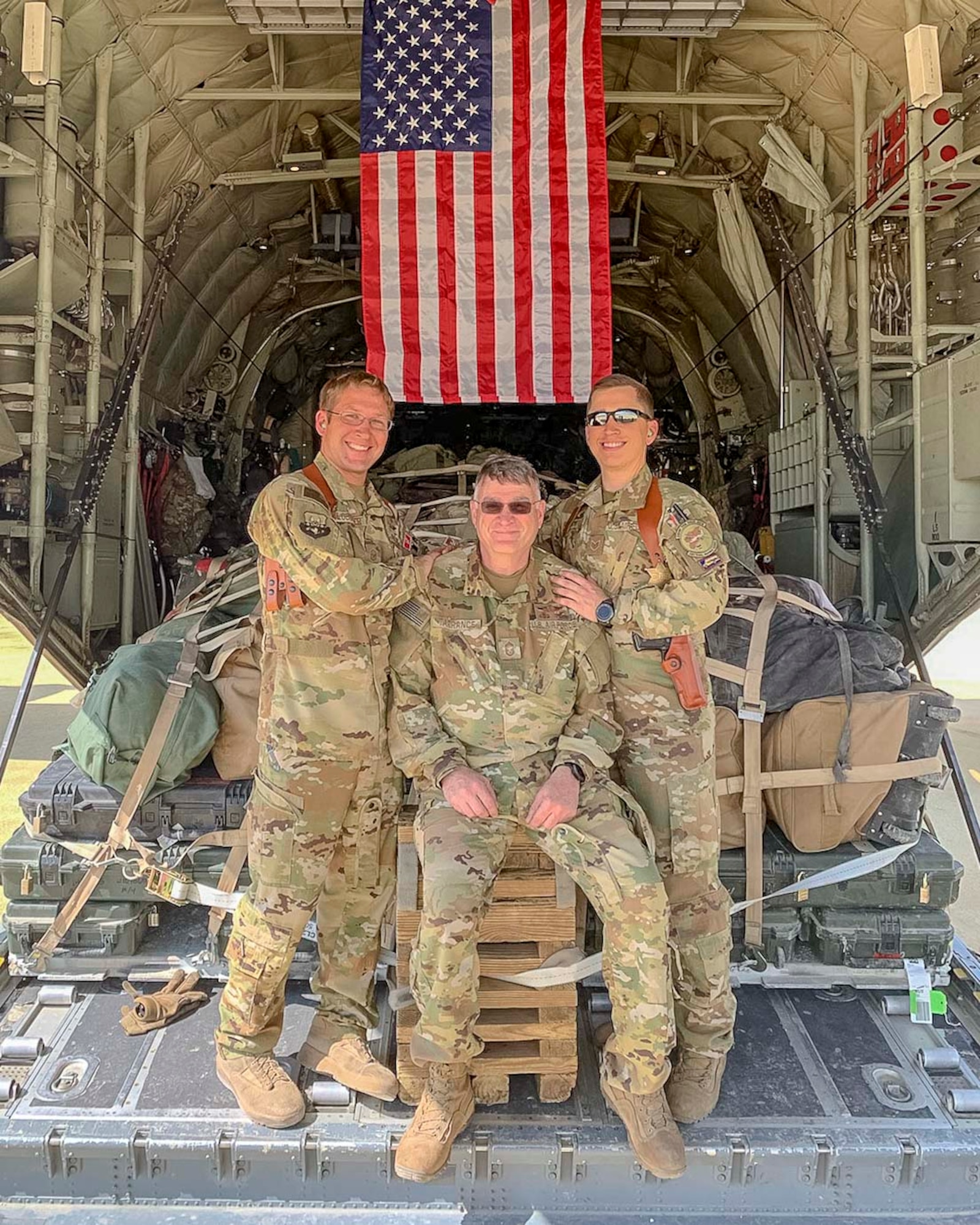 Air Force Reserve Master Sgt. Scott Klobucher (left) and Staff Sgt. Christopher James (right) poses with Chief Master Sgt. Donald Tarrance on the back of a C-130J Hercules loaded with cargo while deployed to Syria in 2019. Tarrance has served for over 40 years in a variety of positions and statuses. (Courtesy photo)