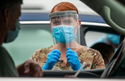 Pfc. Kelly Buterbaugh, a combat medic with the Delaware Army National Guard, gives instructions to a motorist during a drive-thru coronavirus testing mission at the University of Delaware's Science, Technology and Advanced Research Campus in Newark, Delaware, May 29, 2020. About 25 Soldiers and Airmen with the Delaware National Guard supported the saliva-based testing of roughly 400 people at the STAR Campus location.