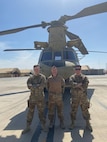 Three Airmen posing in from of a U.S. Army helicopter