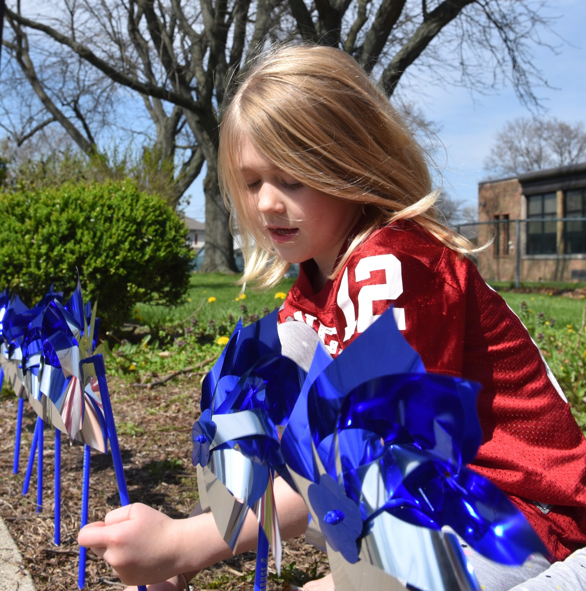 Child places blue pinwheel in ground.