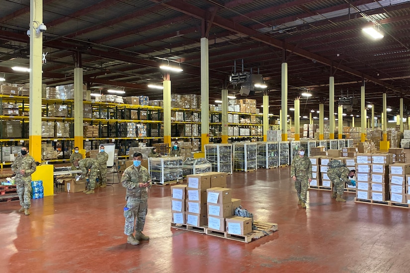 Service members work in a large warehouse.