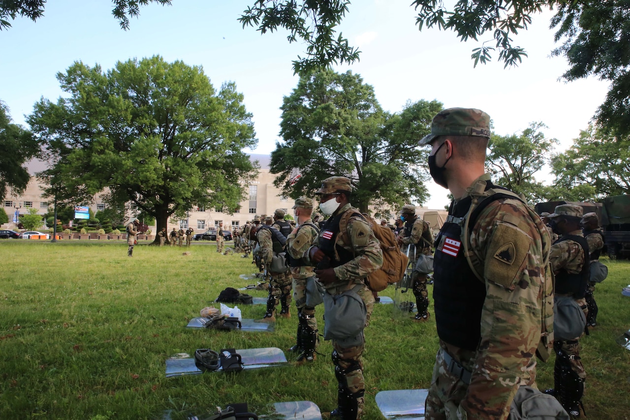 Soldiers face a crowd at night.