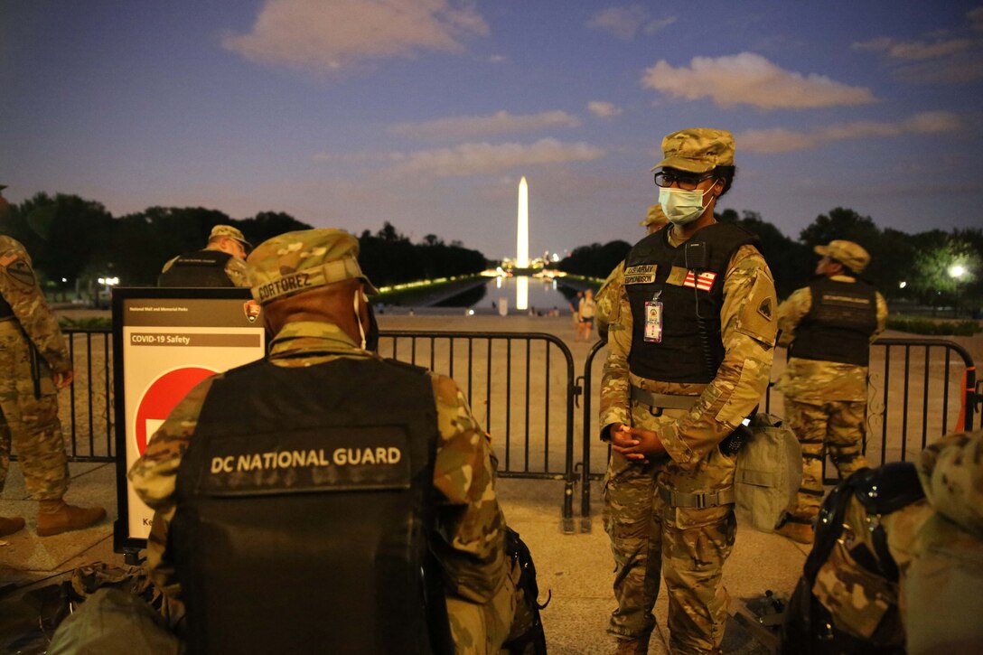 Soldiers stand with the Washington Monument in the background.