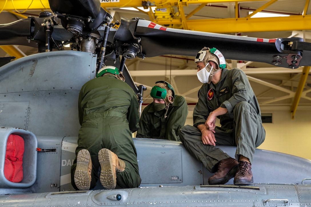 hree Marine Corps students work on a helicopter.