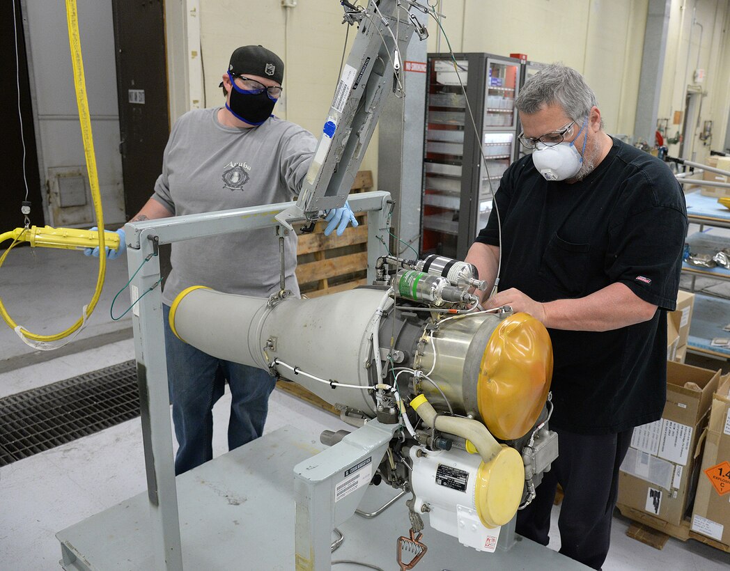 582 Missile Maintenance Squadron liquid engine rocket fuel mechanics, Jennifer McClellan (left) and Kevin O’Donnell, maintain their social distance while preparing an F-107 turbofan engine for placement into a shipping container on Apr. 28, 2020, at Hill Air Force Base, Utah.