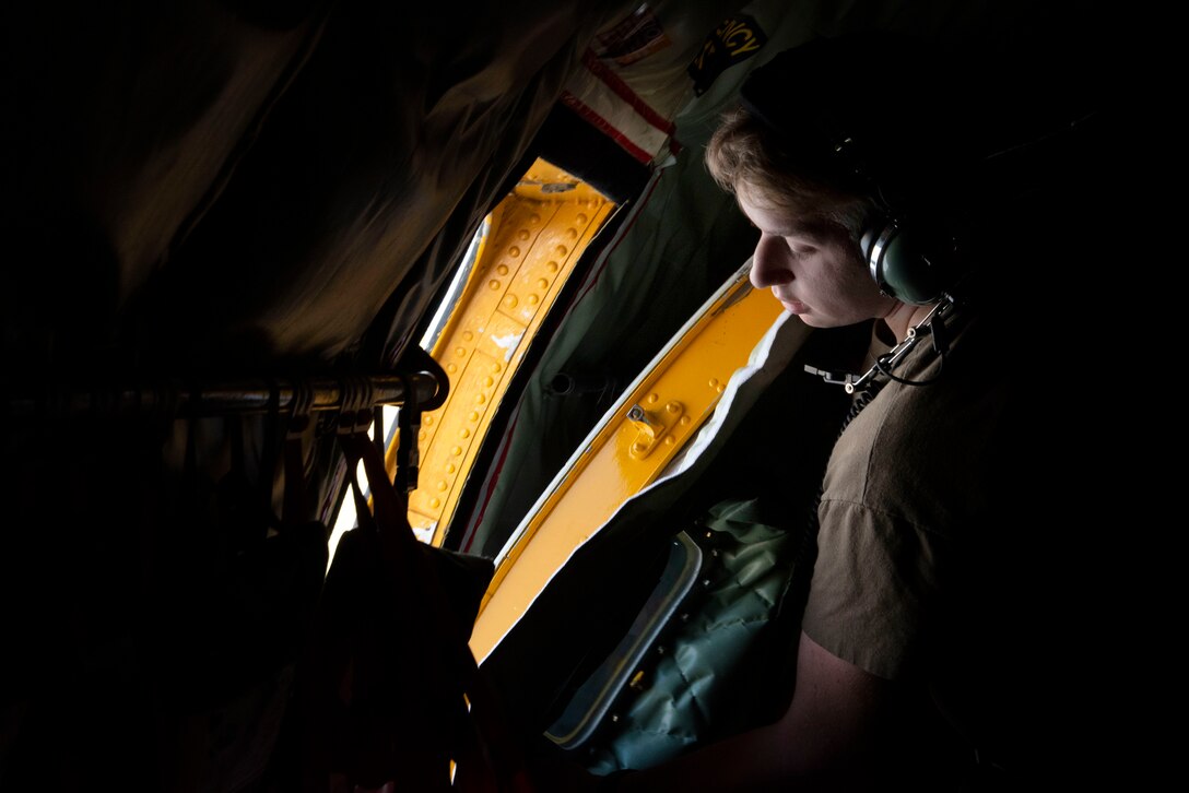 Photo of an Airman looking out the opening of an aircraft