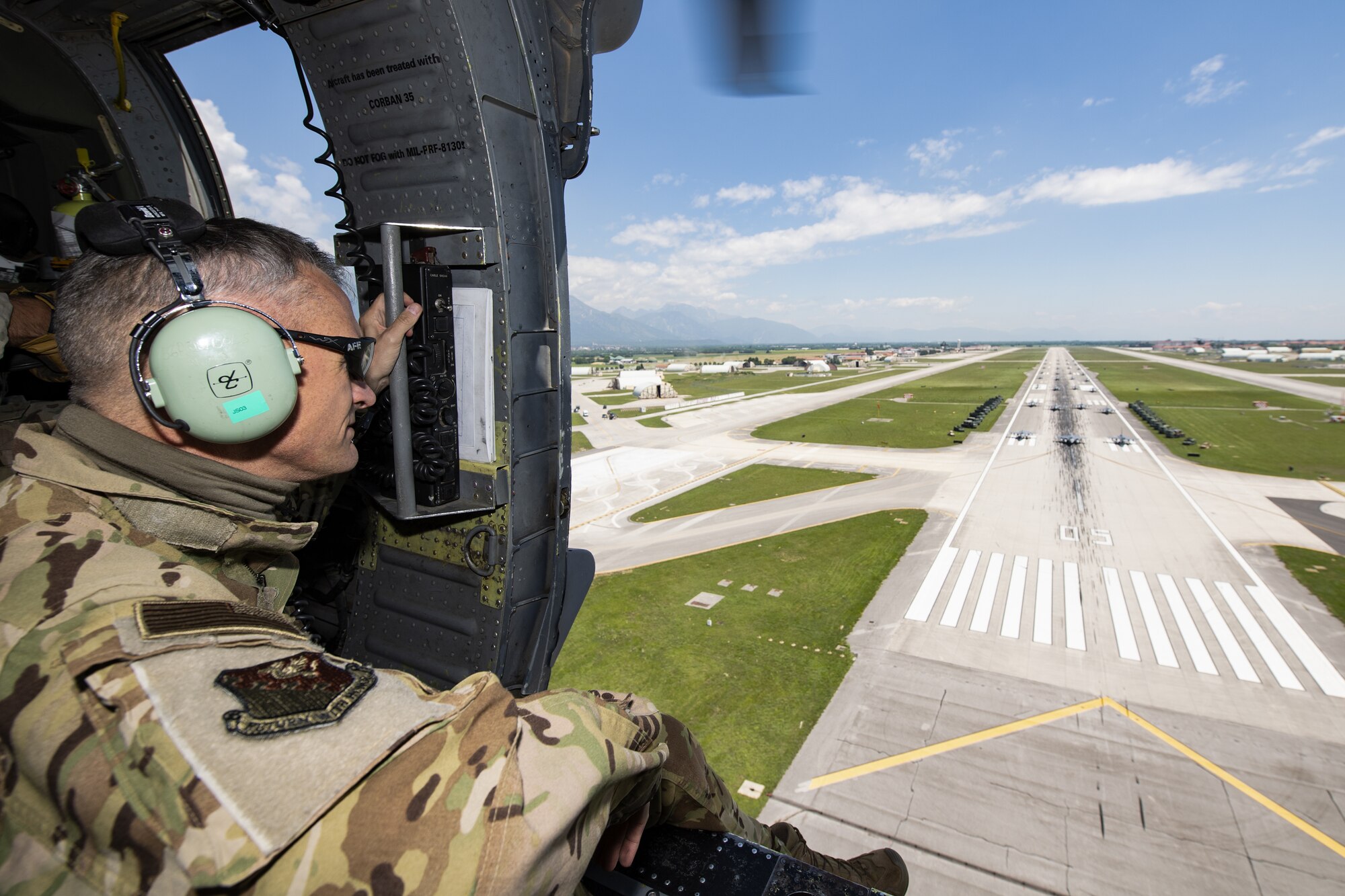 U.S. Air Force Brig. Gen. Daniel T. Lasica, 31st Fighter Wing commander, overlooks an elephant walk while on an HH-60G Pave Hawk helicopter over Aviano Air Base, Italy, June 1, 2020. Elephant walks are a show of force, demonstrating the might and power of the U.S. Air Force and its bases. (U.S. Air Force photo by Airman Thomas S. Keisler IV)