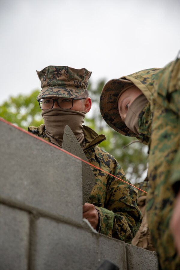 Lance Cpl. Tristan Pickens, left, and Lance Cpl. Tyler Alexander, right, combat engineers with Special Purpose Marine Air-Ground Task Force - Southern Command, level a cylinder block wall during a general exercise at Marine Corps Base Camp Lejeune, North Carolina, April 15, 2020. Pickens, alongside the other combat engineers, leveled the wall to help their construction project maintain its overall structural integrity. The GENEX includes training events such as engineering projects and evacuation control center training scenarios that will help build the SPMAGTF-SC for their final certification exercise. These training events also provide the Marines and Sailors with real-world scenarios to prepare them for their deployment to assist partner nation militaries in Latin America and the Caribbean. Pickens is a native of Jefferson, Oregon. Alexander is a native of Scappoose, Oregon. (U.S. Marine Corps photo by Cpl. Benjamin D. Larsen)