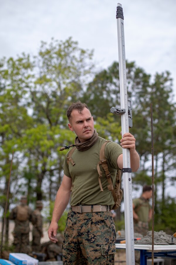 Cpl. Blake Thompson, a combat engineer with Special Purpose Marine Air-Ground Task Force - Southern Command, checks the level of the first row of cylinder blocks during the general exercise at Marine Corps Base Camp Lejeune, North Carolina, April 13, 2020. Thompson ensured that the walls would align evenly, as it could delay the project if the cylinder blocks didn’t fit correctly. The GENEX includes training events such as engineering projects and evacuation control center training scenarios that will help build the SPMAGTF-SC for their final certification exercise. These training events also provide the Marines and Sailors with real-world scenarios to prepare them for their deployment to assist partner nation militaries in Latin America and the Caribbean. Thompson is a native of Portland, Oregon. (U.S. Marine Corps photo by Cpl. Benjamin D. Larsen)