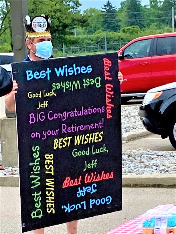 Jeffrey Law displays giant poster received from team mates on day of surprise AFMC parking lot gala to celebrate retirement after 36 years of service