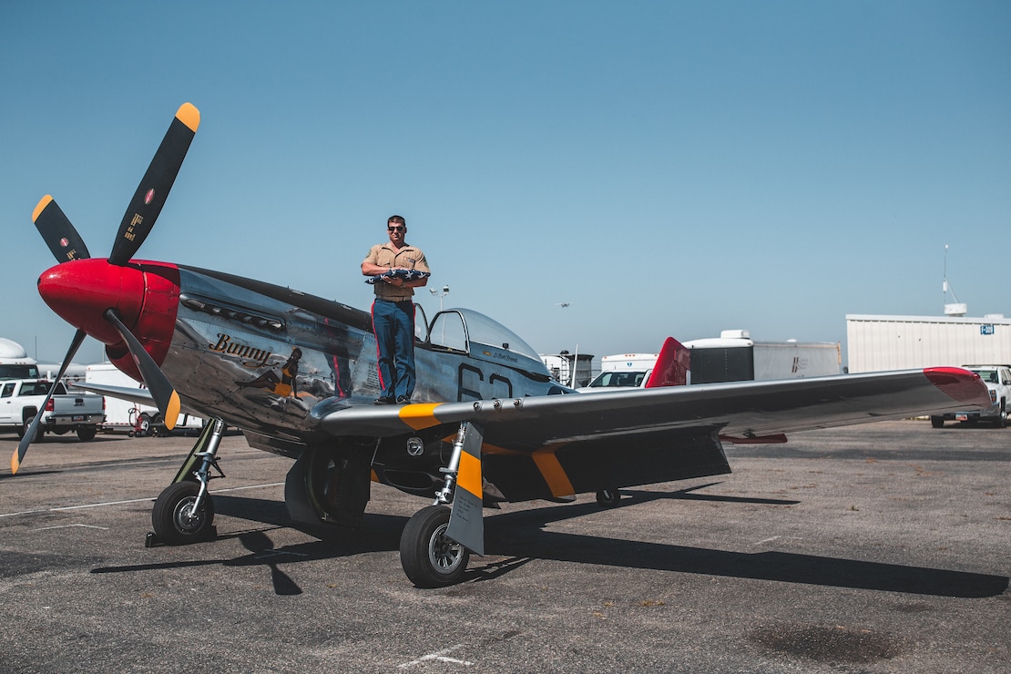 A U.S. Marine poses for a photograph on a P-51 Mustang with the burial flag of a fallen American service member after a Memorial Day ceremonial flyover at the Chino Municipal Airport, Calif., May 25.