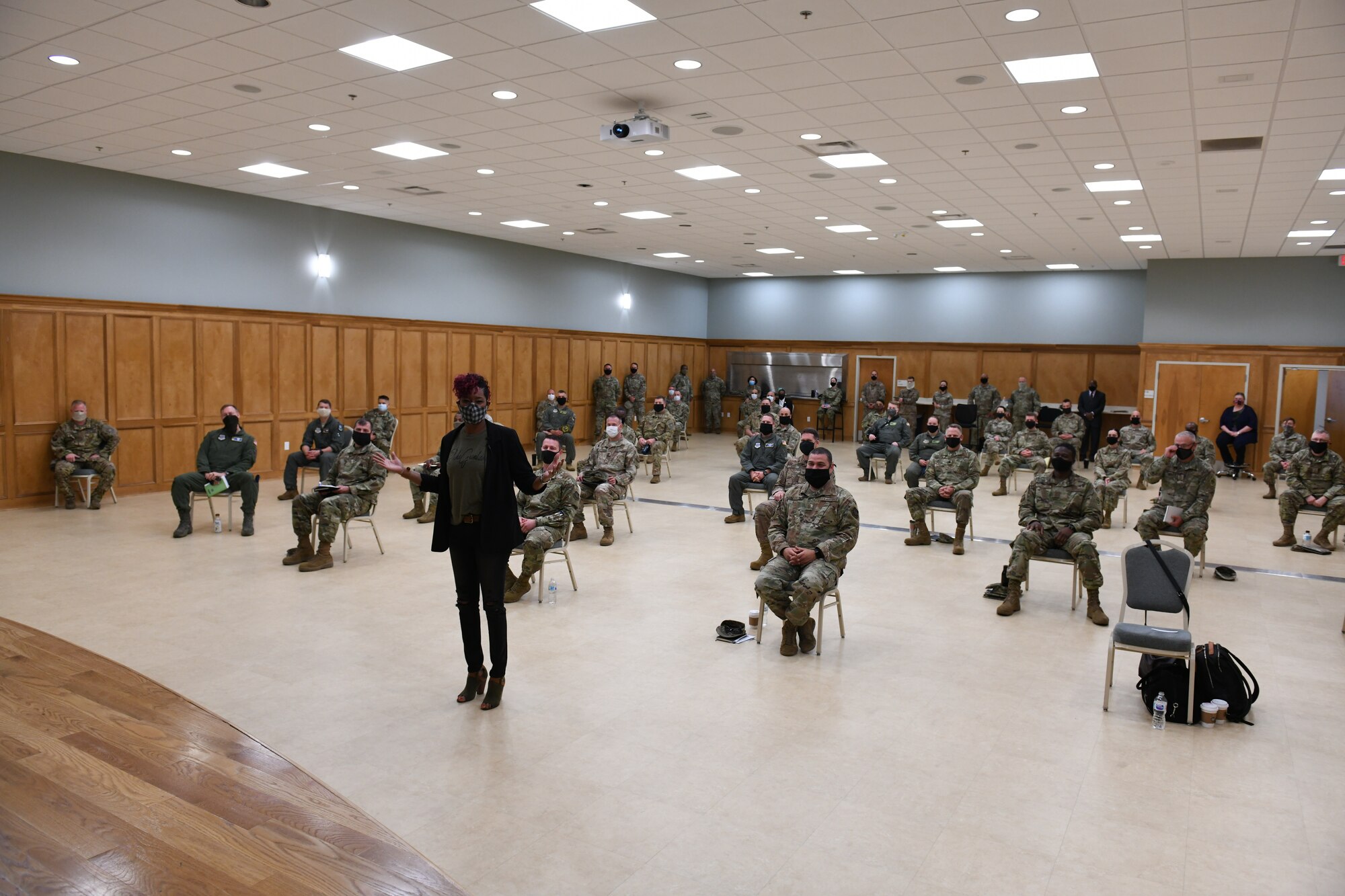 A woman stands in front of the room full of command teams