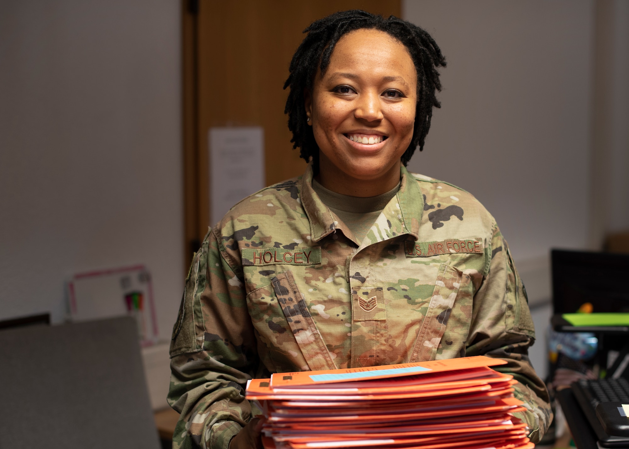 U.S. Air Force Staff Sgt. Jasmine Holcey, 786th Force Support Squadron relocations supervisor, poses for a photo holding a day’s worth of personnel out-processing folders at Ramstein Air Base, Germany, June 1, 2020.