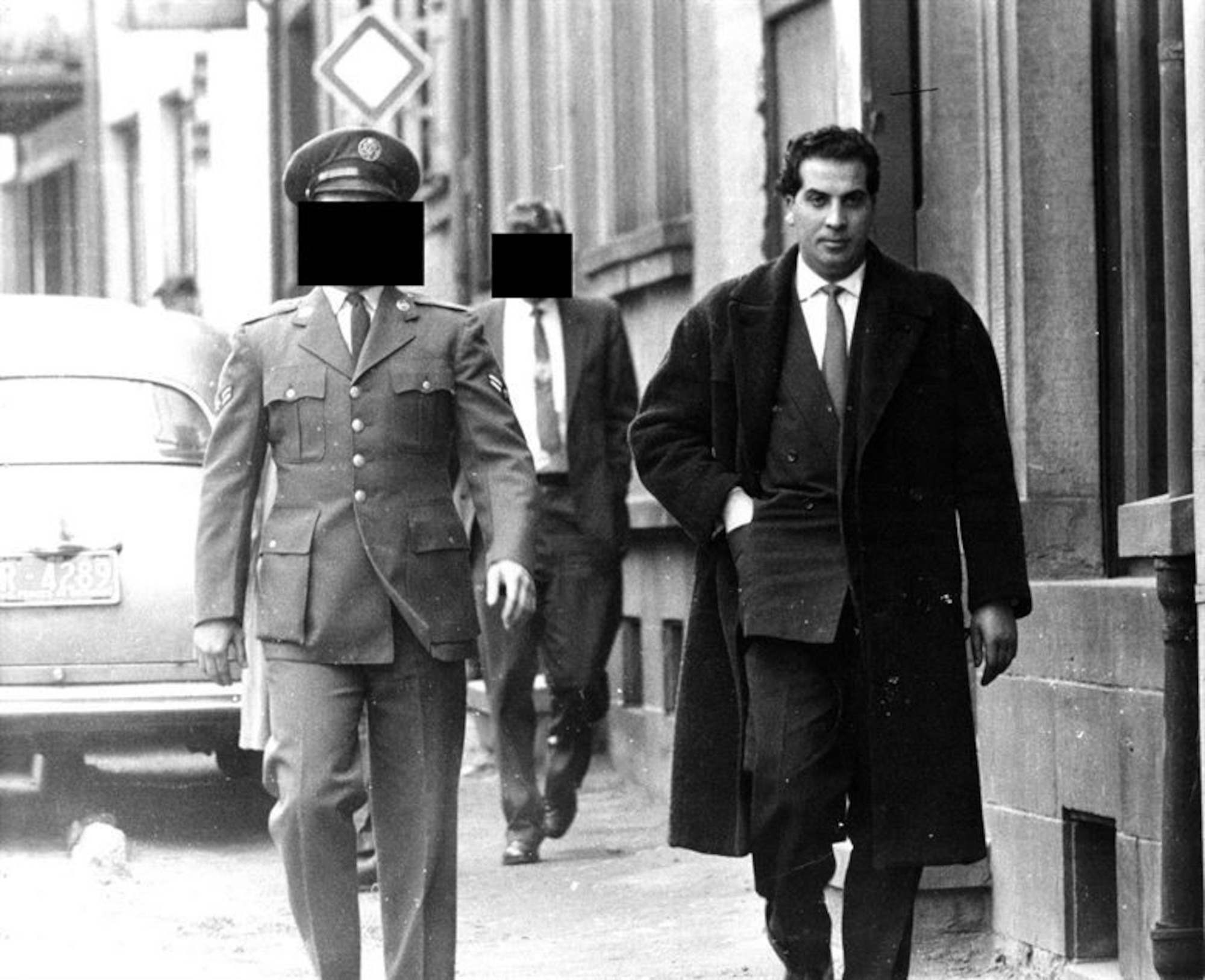In 1959, an Algerian terrorist (right) claimed to be a member of the Front de la Libération Nationale (FLN) and attempted to purchase machine guns and pistols from the U.S. Airman (left), near Ramstein Air Base, Germany. The Airman alerted OSI, who in coordination with the French and German police, recorded and photographed the men throughout an investigation. The man behind the Airman is an OSI agent. (U.S. Air Force photo)