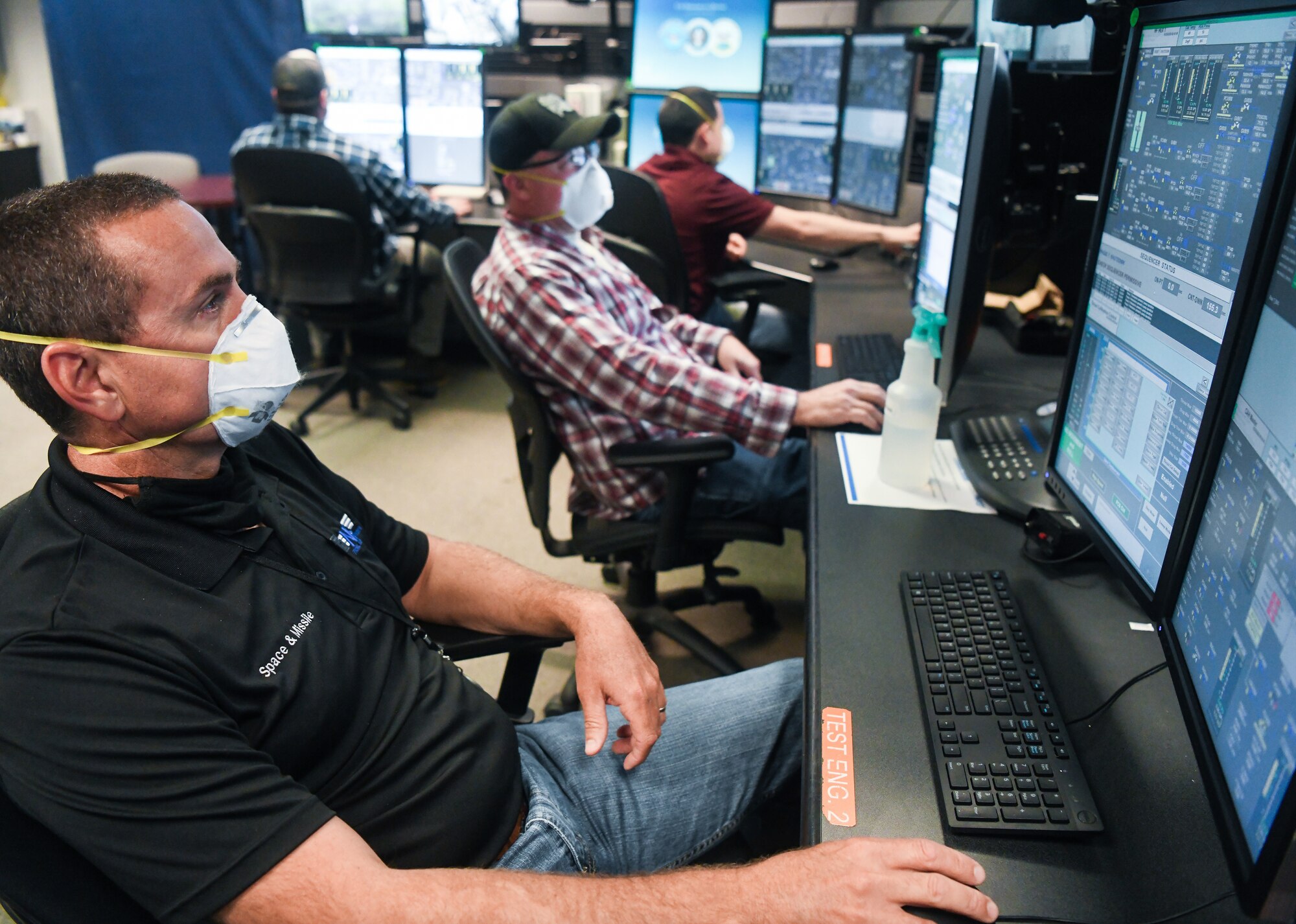 Daryl Osteen, left, a test operations engineer, John VanScoten, an outside machinist, and other Team AEDC personnel work in the control room of the Arnold Engineering Development Complex (AEDC) Aerodynamic and Propulsion Test Unit (APTU), May 20, 2020, while wearing masks to help mitigate risk associated with the coronavirus pandemic. The APTU team has performed their tasks, providing hypersonic testing capabilities, without interruption during the pandemic. Hypersonics is considered a critical field for national defense. (U.S. Air Force photo by Jill Pickett)