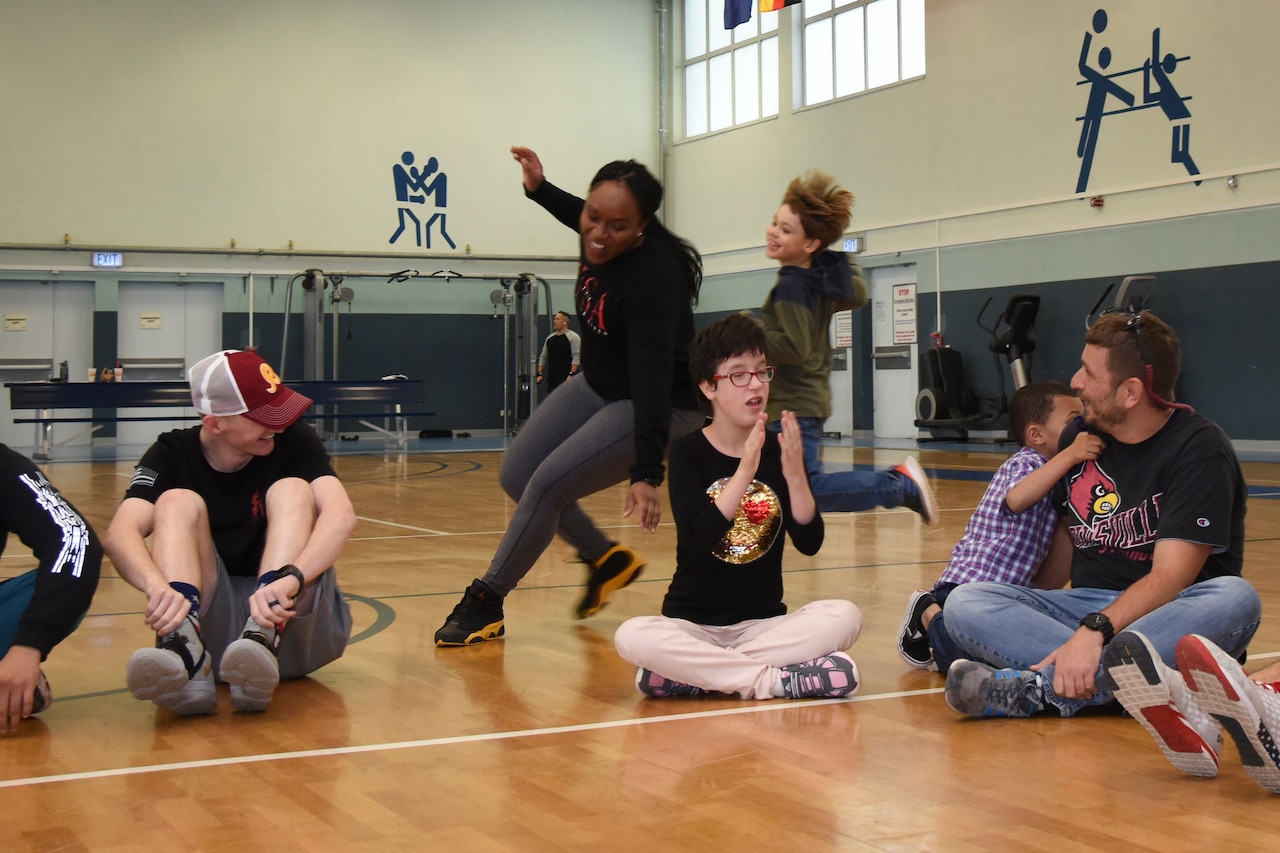 Children and adults play in a gym.