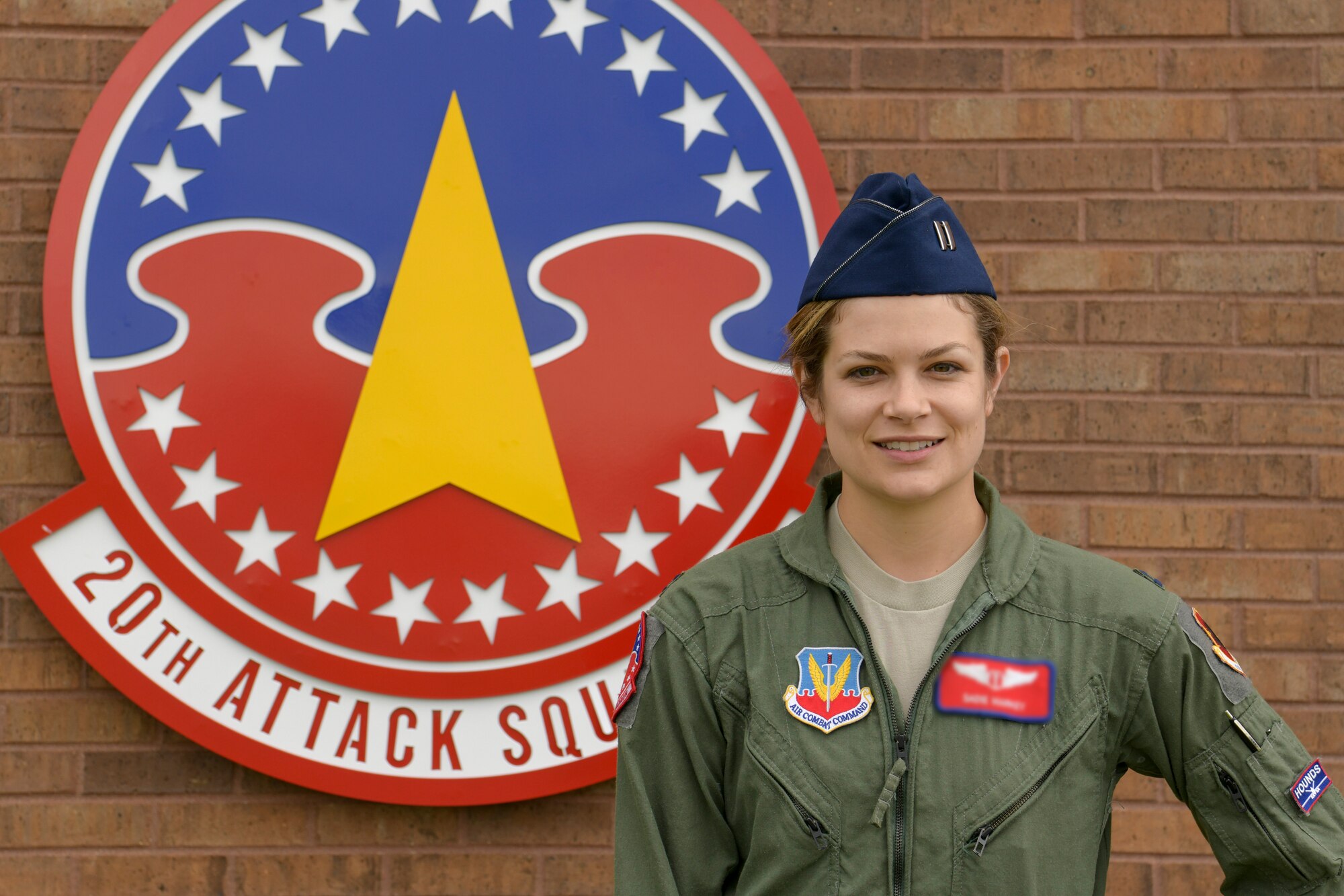 U.S. Air Force Capt. (Dr.) Sadie, 20th Attack Squadron medical element flight surgeon, stands in front of the 20th ATKS sign at Whiteman Air Force Base, Missouri, May 6, 2020. Markey developed procedures and authored policies for the squadron to combat COVID-19. U.S. Air Force photo by Staff Sgt. Dylan Nuckolls) (This photo has been altered for security purposes by blurring out the name badge)