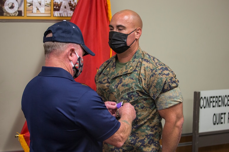 U.S. Marine Corps Maj. Craig Sisson with Marine Corps Air Station (MCAS) Yuma, receives a Purple Heart from Col. David A. Suggs, commanding officer, MCAS Yuma, at the MCAS Yuma Headquarters building, June 1, 2020. Maj. Sisson received the Purple Heart for wounds sustained while deployed in support of Operation Enduring Freedom on May 13, 2013. (U.S. Marine Corps photo by Lance Cpl John Hall)