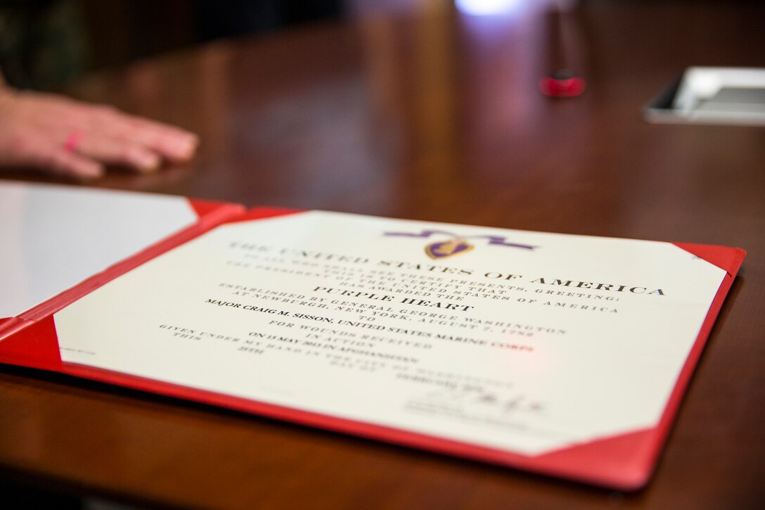 U.S. Marine Corps Maj. Craig Sisson with Marine Corps Air Station (MCAS) Yuma, receives a Purple Heart from Col. David A. Suggs, commanding officer, MCAS Yuma, at the MCAS Yuma Headquarters building, June 1, 2020.
