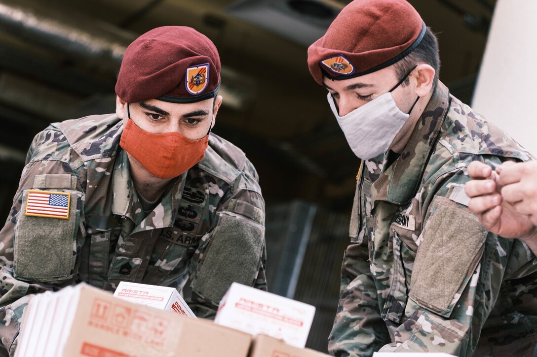 Service members in masks help prepare boxes for distribution.