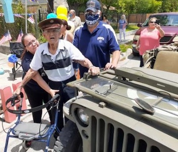 World War II veteran Raul Garza stands alongside a World War II-era jeep at his birthday drive-by party.