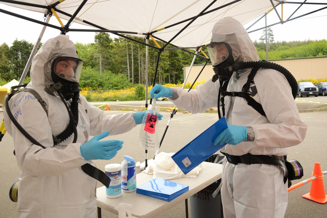 Guardsmen in full protective gear handle coronavirus test samples.