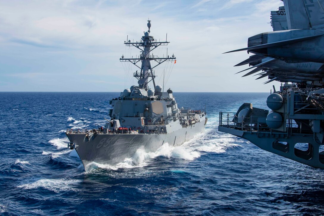 A ship travels through waters next to another ship.