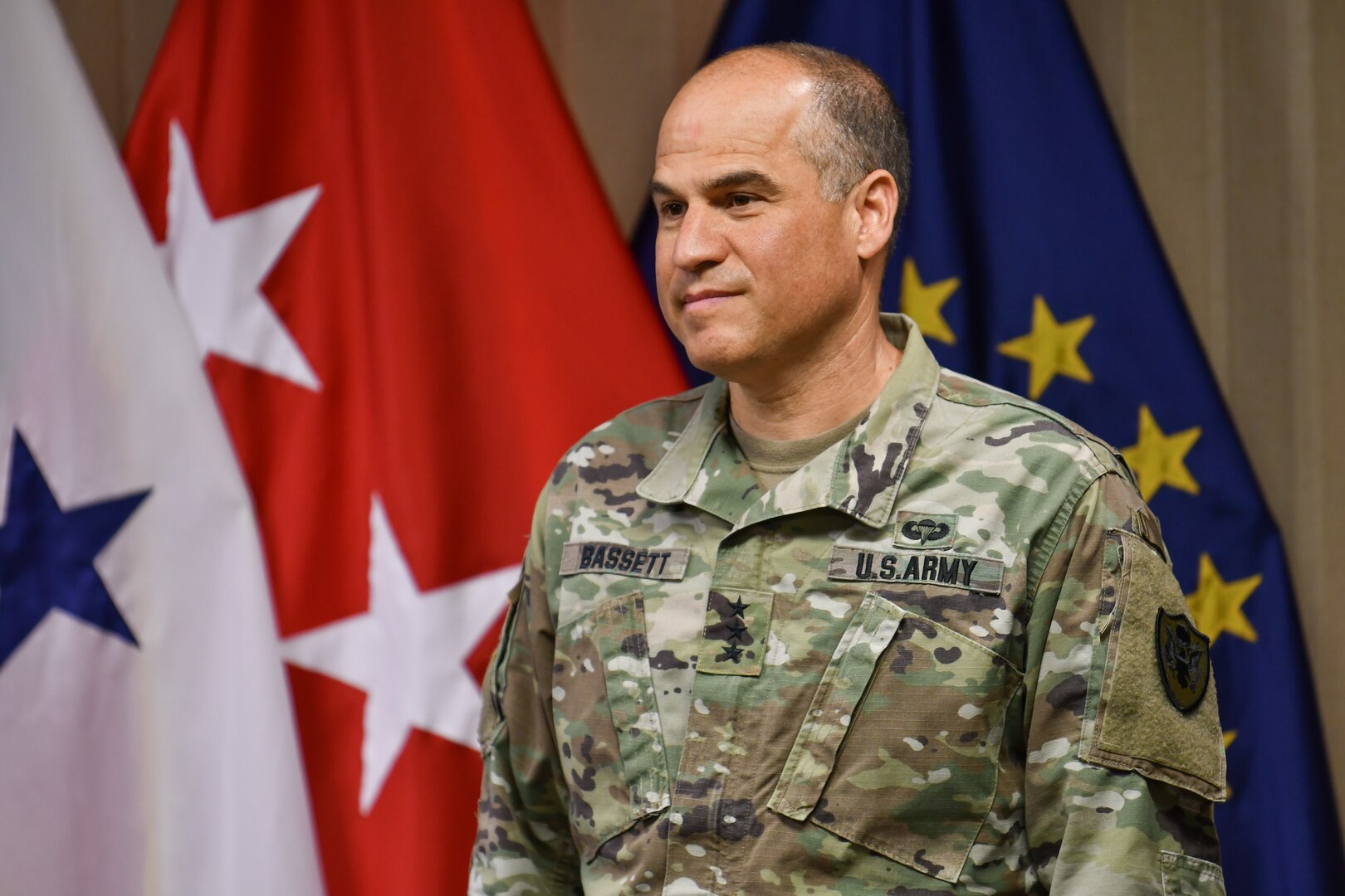 Army general stands in front of flags