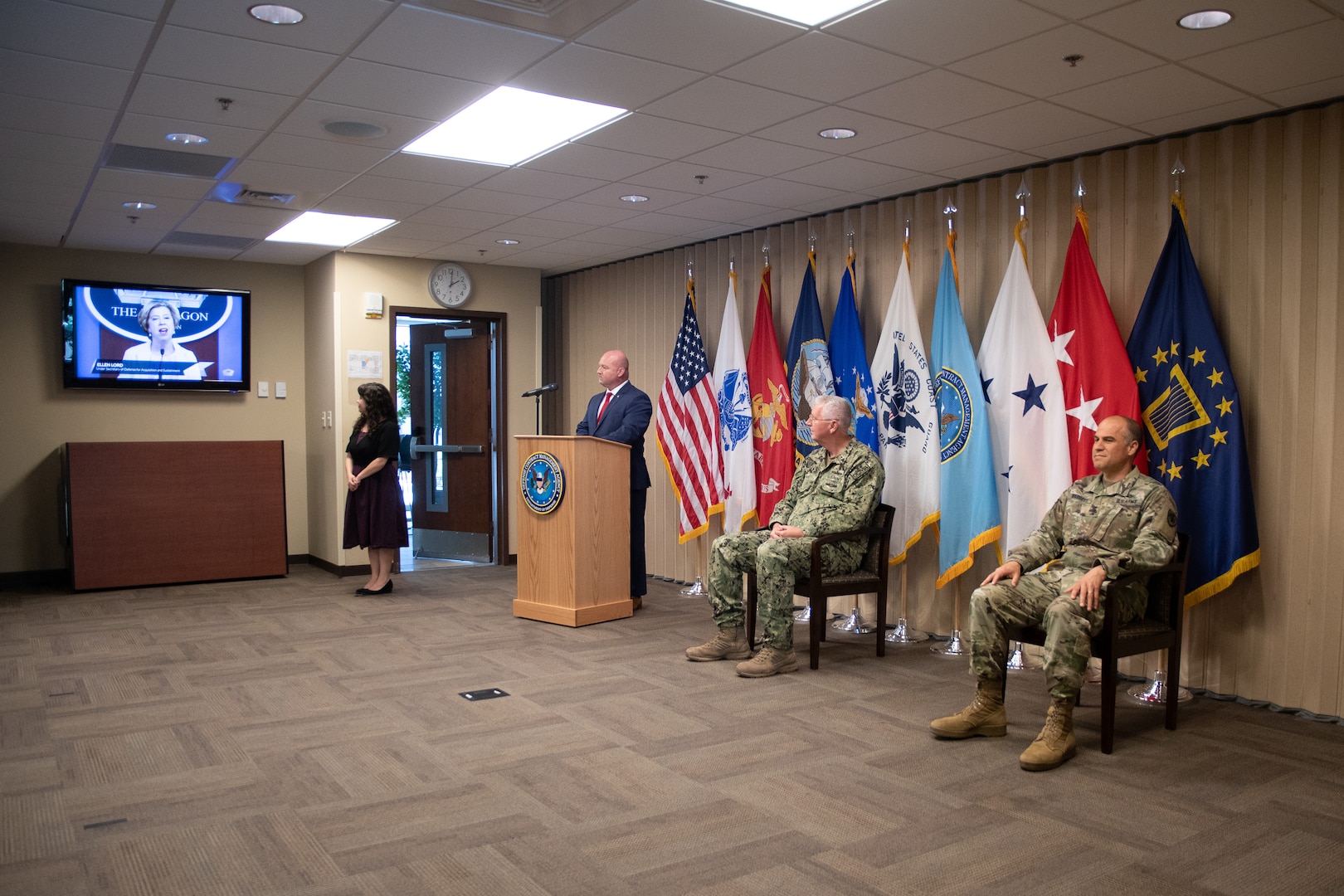 Four people watch a television screen that says Pentagon