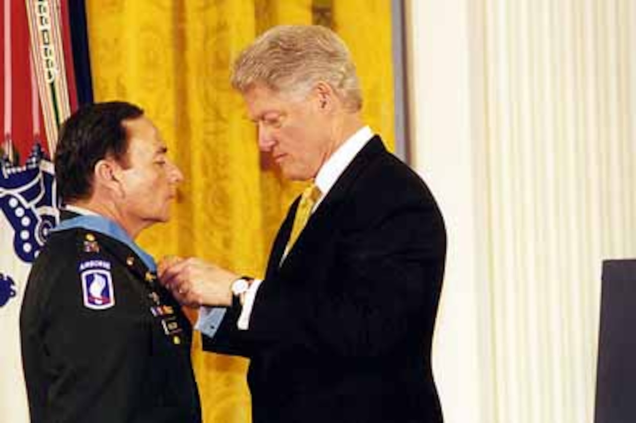A man adjusts a medal around another man’s neck.