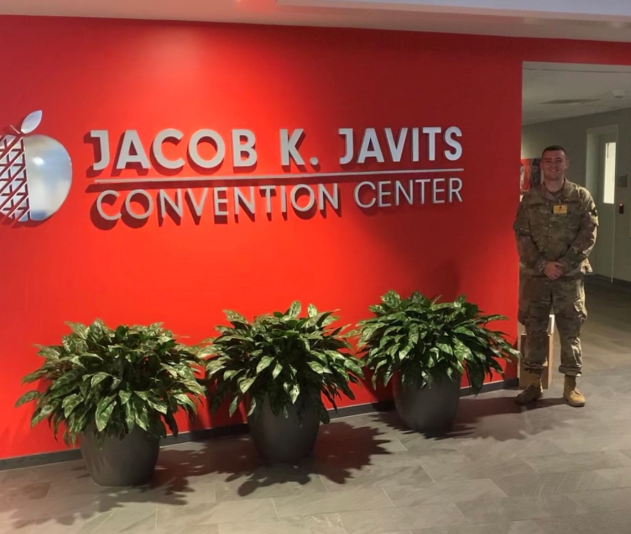 A soldier stands beside Jacob K. Javits Convention Center sign.