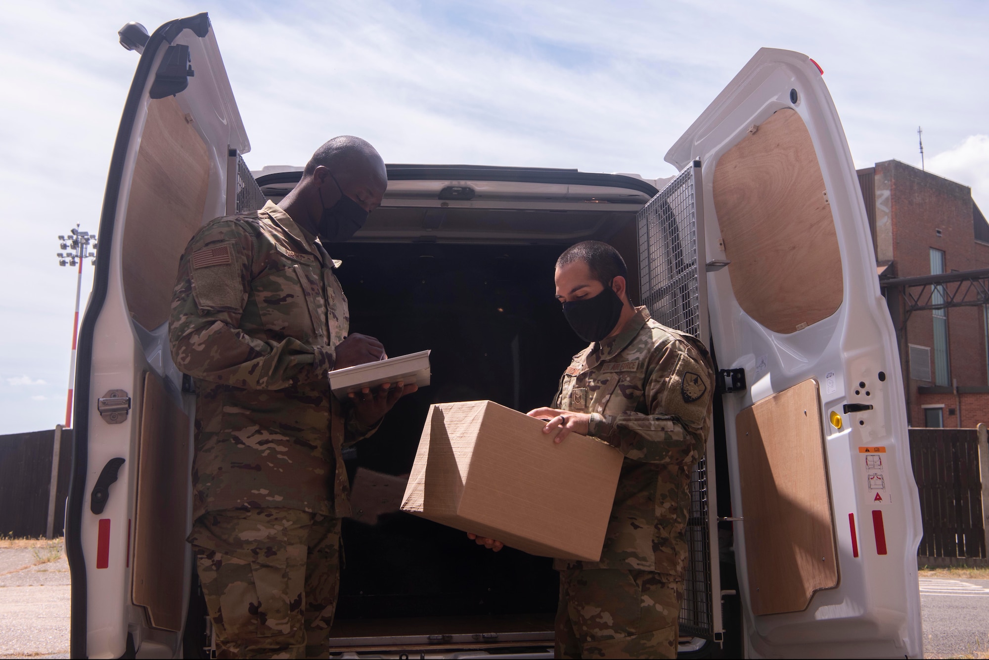 Staff Sgt. Isaac Darko and Staff Sgt. Isaac Portocarrero, Defense Courier Station Mildenhall defense couriers, load packages into a mission vehicle at RAF Mildenhall, England, June 2, 2020. Factors such as the size of the asset and delivery destination dictate the mode of transportation defense couriers use to move items. (U.S. Air Force photo by Airman 1st Class Joseph Barron)