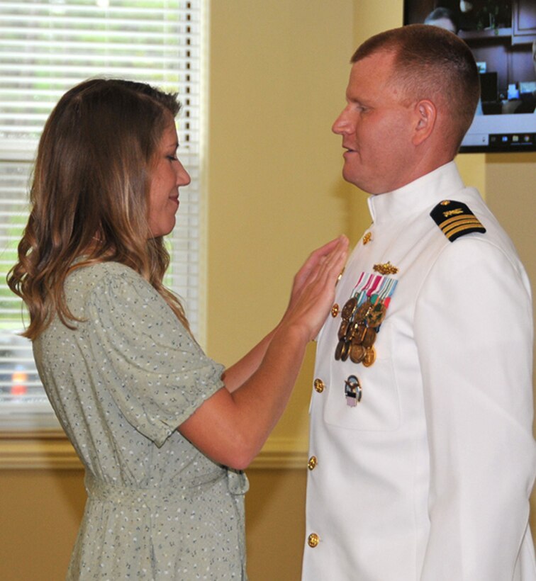 Brittanie May places command pin on Navy Cmdr. Isaac May's uniform