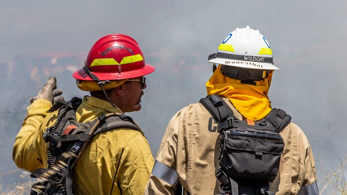 A firefighter with the Camp Pendleton Fire Department explains the scheme of maneuver to another firefighter during a controlled burn training exercise on Marine Corps Base Camp Pendleton, Calif., June 3.