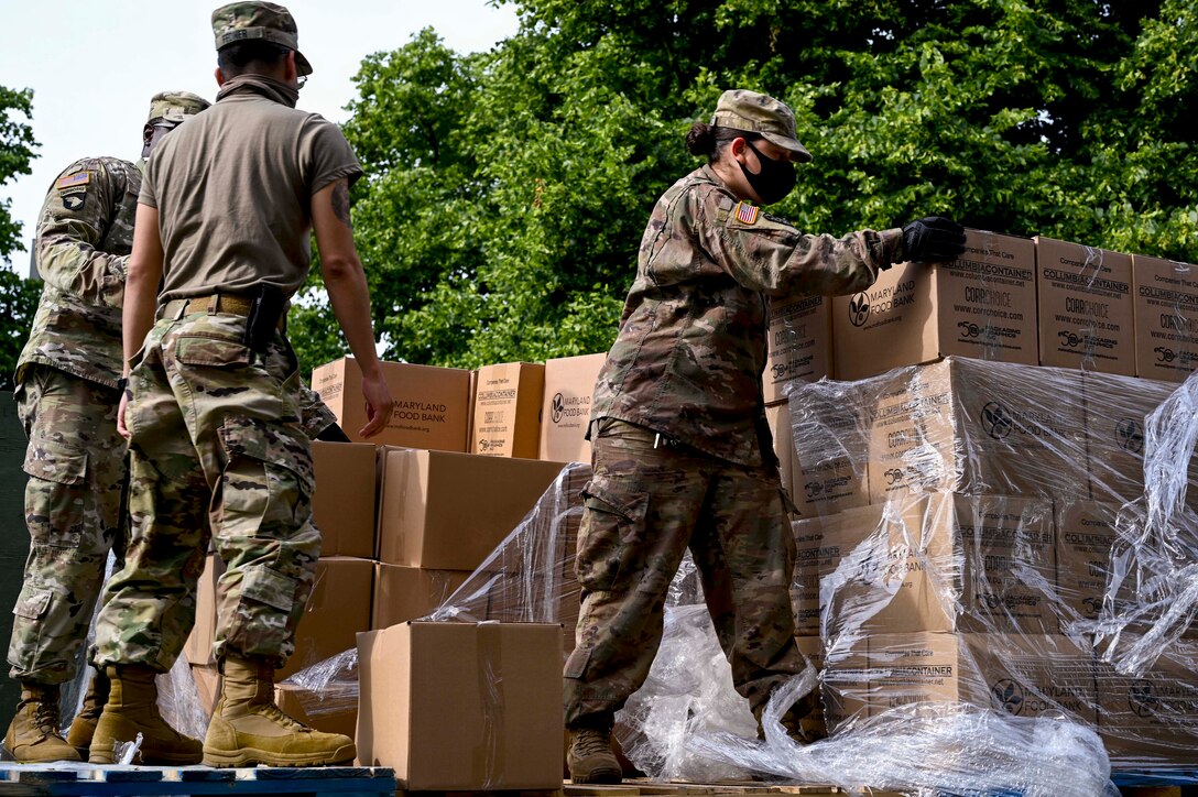 National Guardsmen in protective gear pick up boxes.