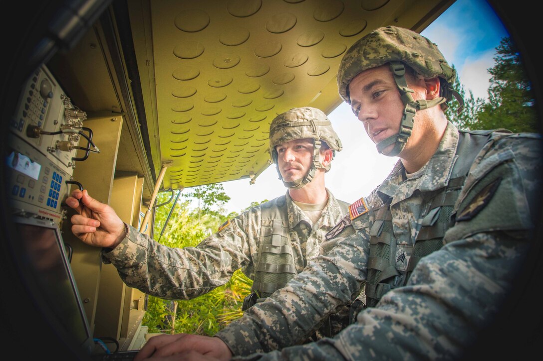 Two soldiers work with communications equipment.