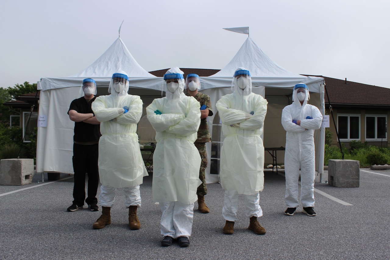 Soldiers wearing personal protective equipment pose with their arms folded.