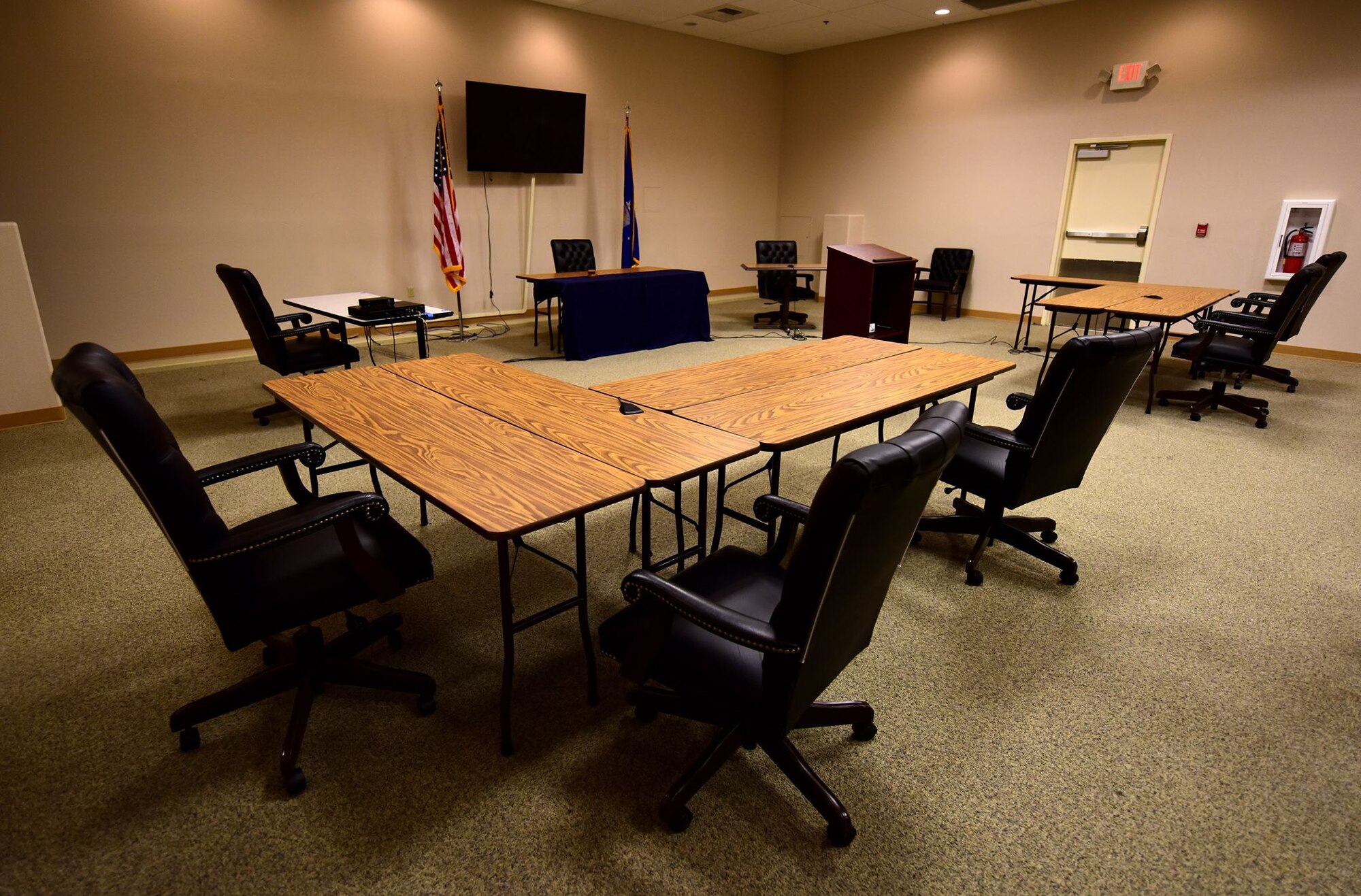 Tables, chairs, and flags are set up in a room to look like a court room.