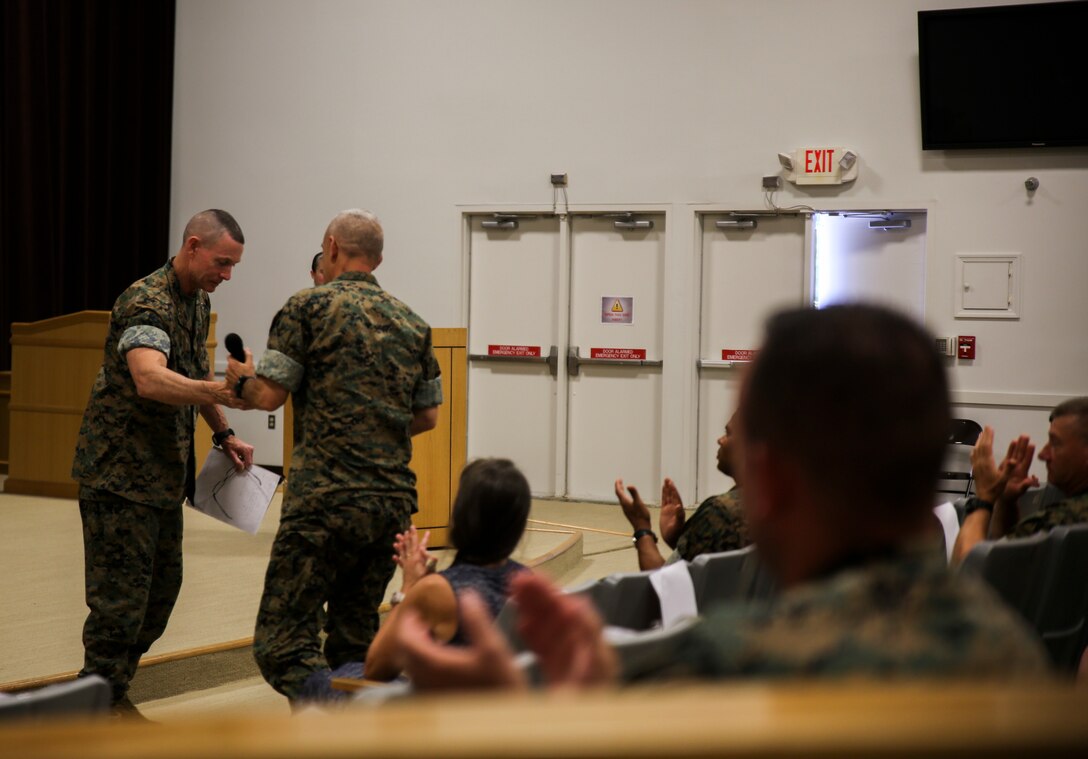 U.S. Marine Corps Maj. Gen. Stephen M. Neary, outgoing commanding general 2nd Marine Expeditionary Brigade, passes the microphone to Brig. Gen. David L. Odom, incoming commanding general of 2nd MEB, during a change of command ceremony at Camp Lejeune, N.C., June 5, 2020. Neary will be the commanding general of U.S. Marine Forces Europe and Africa. (U.S. Marine Corps photo by Lance Cpl. Samuel Lyden)