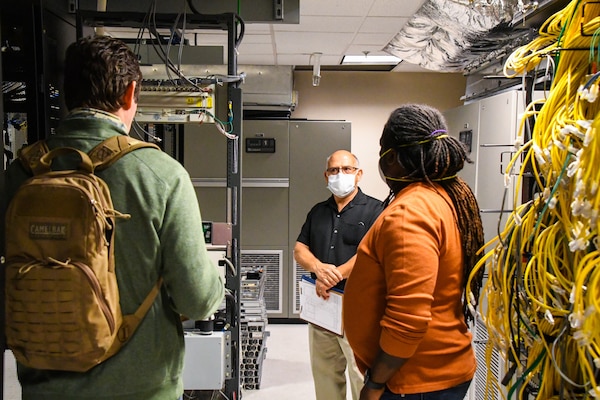 three men talk in a server room