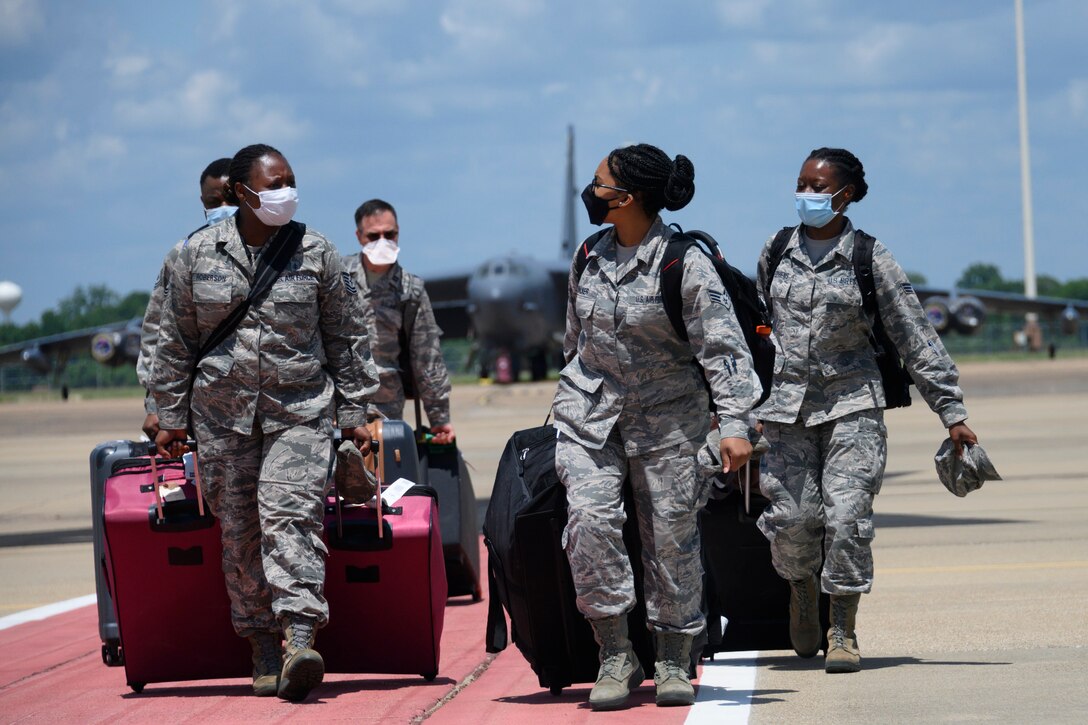 Airman walk across flightline with luggage.
