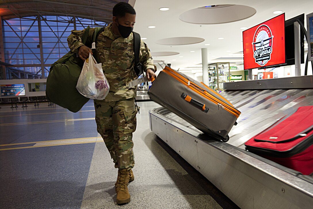 Airman takes luggage from carousel at airport.