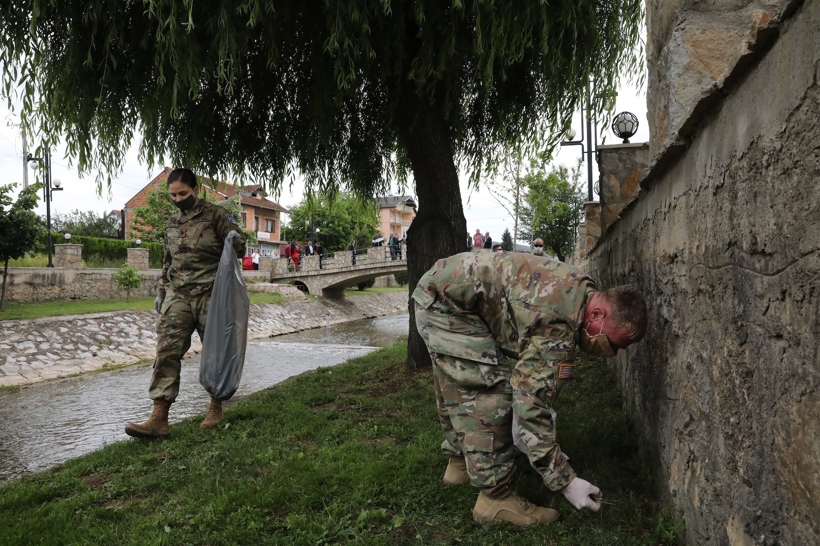 Spc. Jamie Harrison and Sgt. Aaron Crane of Kosovo Force Regional Command East Liaison Monitoring Team “Kilo 20” pick up trash along a creek of Vitina/Viti, Kosovo, June 5, 2020. LMT personnel from “Kilo 20” out of Camp Bondsteel and Maneuver Battalion personnel out of Camp Nothing Hill participated in area beautification in observation of World Environment Day.